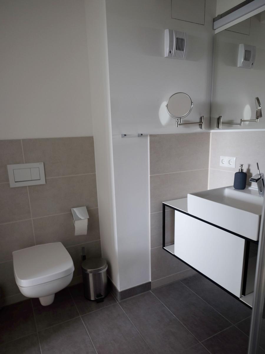 Badezimmer mit Toilette, Waschbecken und Spiegel