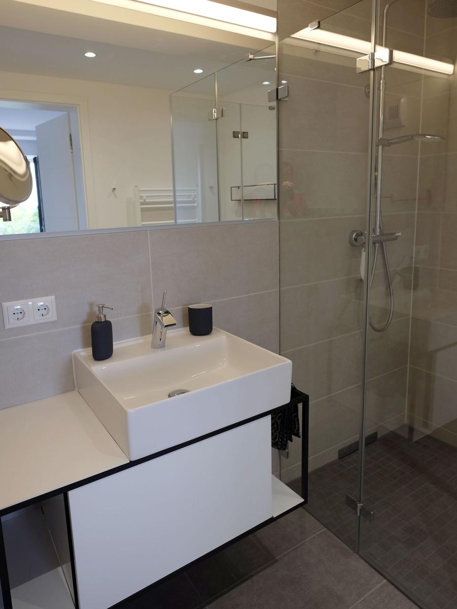 Badezimmer mit Dusche, Waschbecken und Spiegel