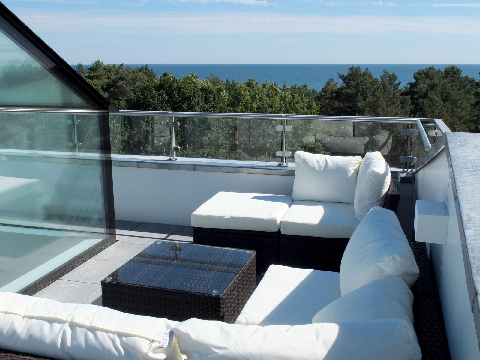 Terrasse mit Sitzgruppe und Meerblick durch Glasgeländer