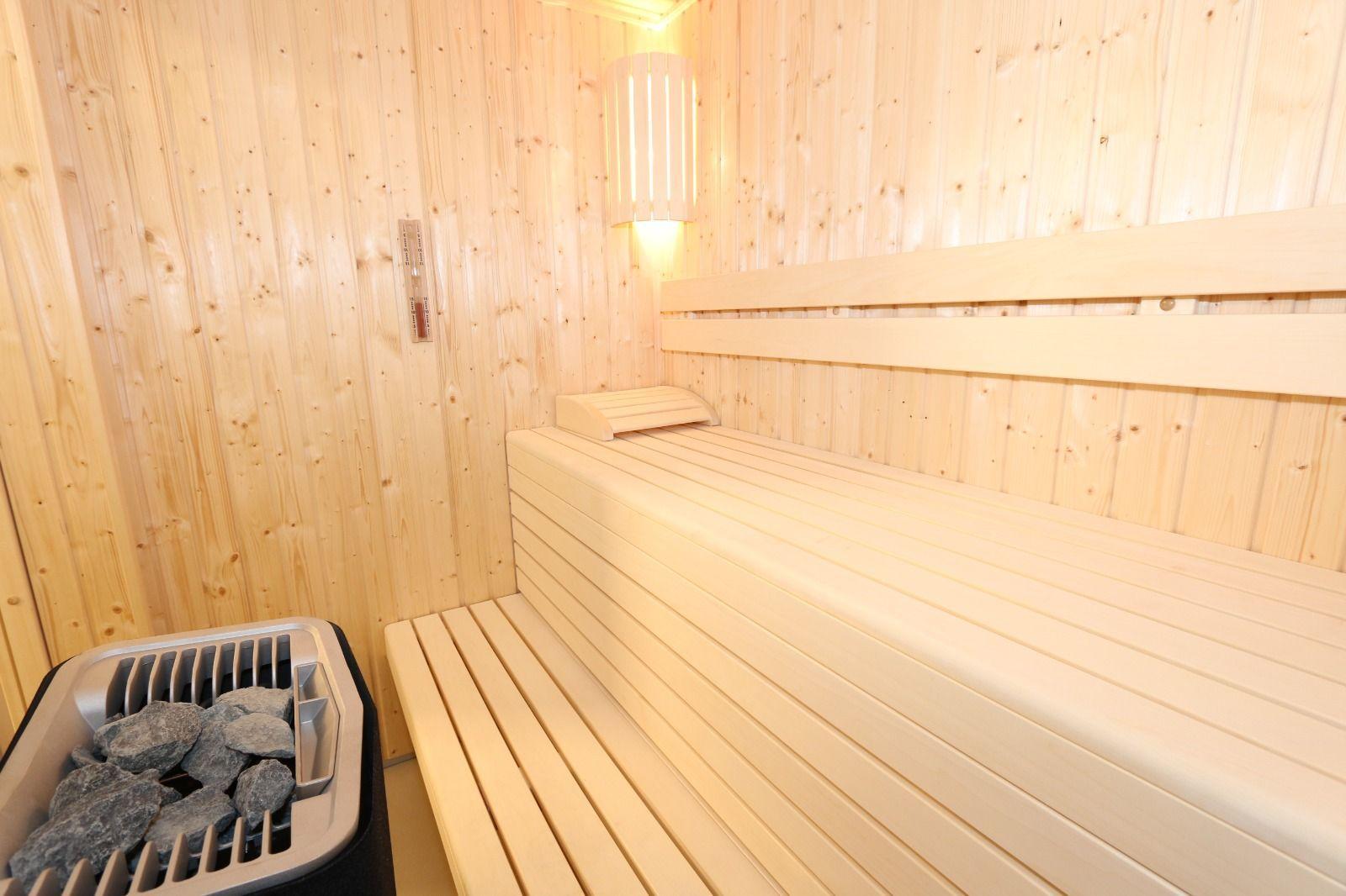 Sauna mit Holzwand, Sitzbank und Steinkasten mit Heizung.