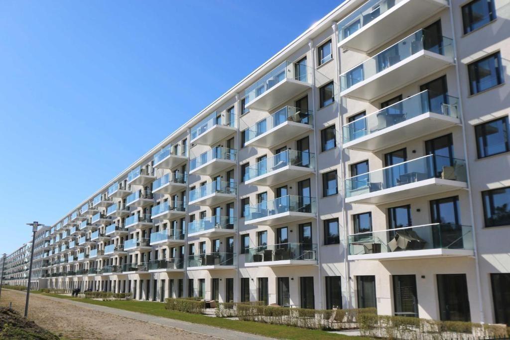 Moderne Wohnanlage mit Balkonen und großen Fenstern unter blauem Himmel.