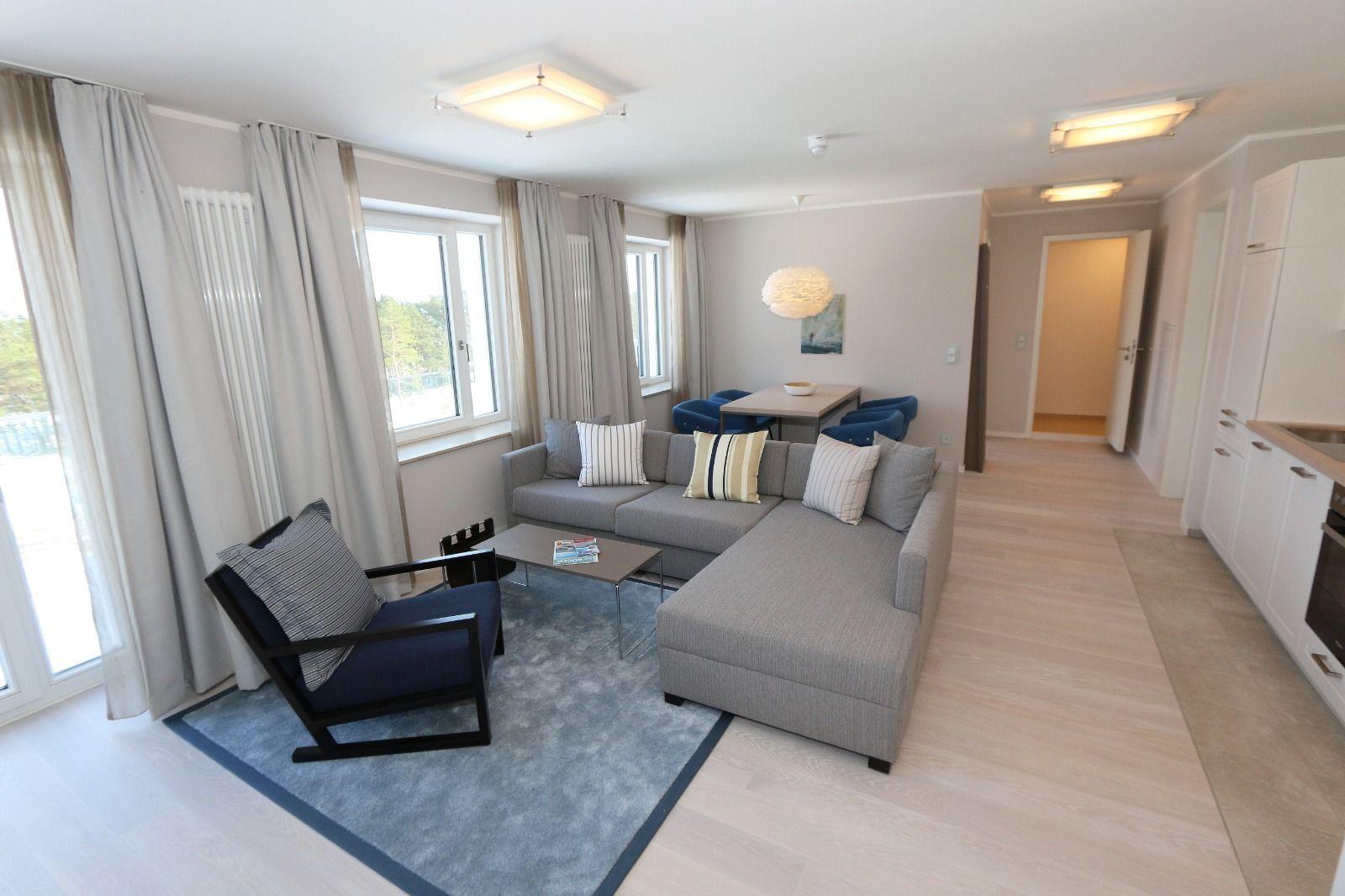Wohnzimmer mit Sofa, Sessel und Küchenbereich