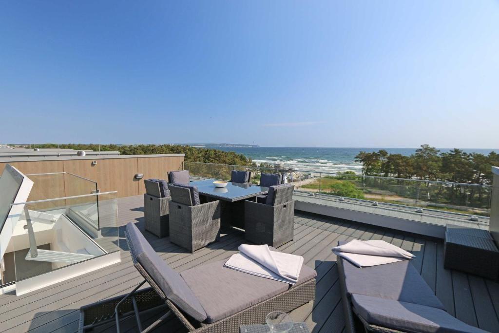 Terrasse mit Sitzgruppe und Meerblick. Holzdeck und Glasgeländer.