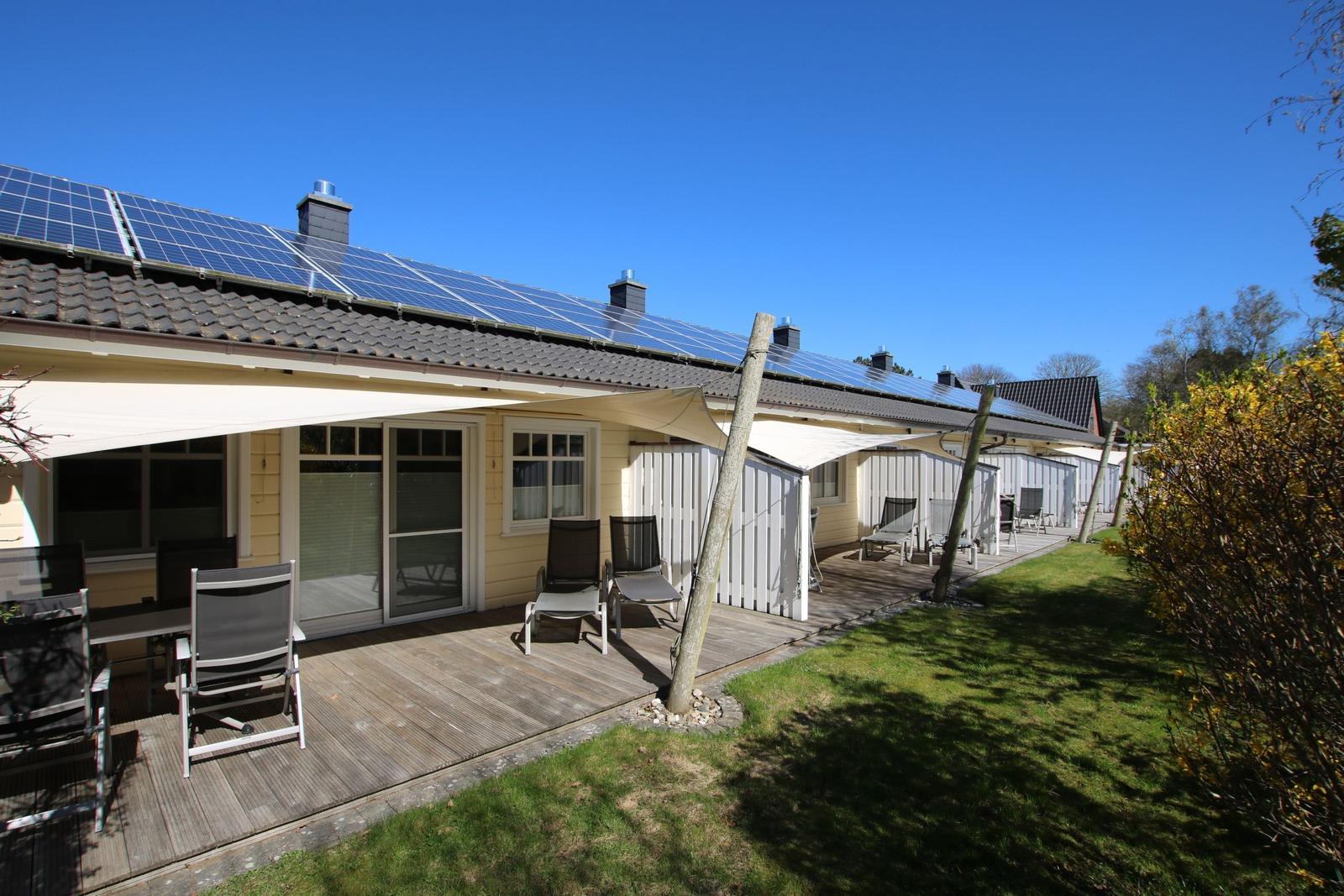 Reihenhaus mit Solaranlage und Terrasse mit Liegestühlen.