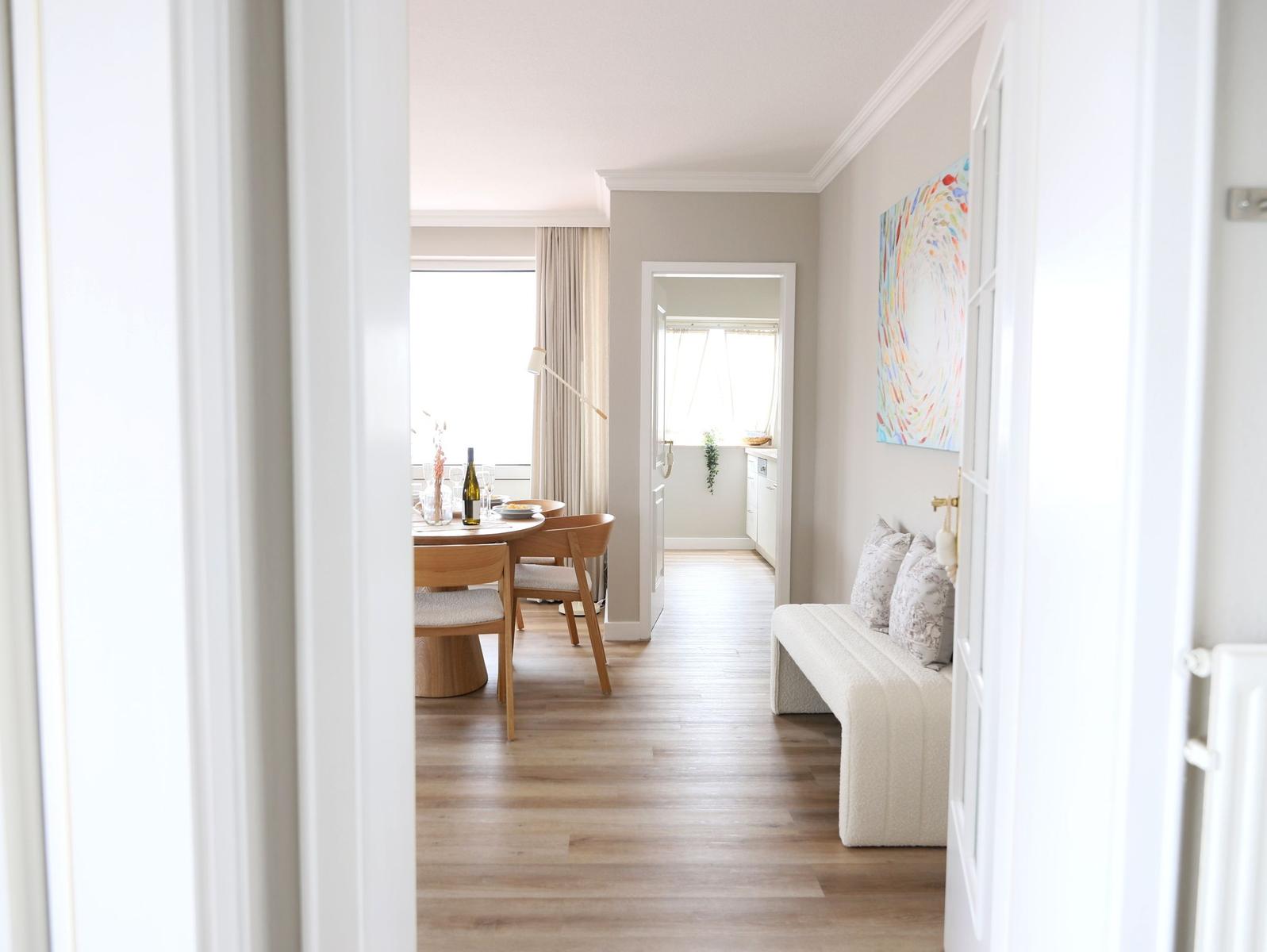 Wohnung mit Essbereich, Sofa und Wandbild. Holzboden und helle Wände.
