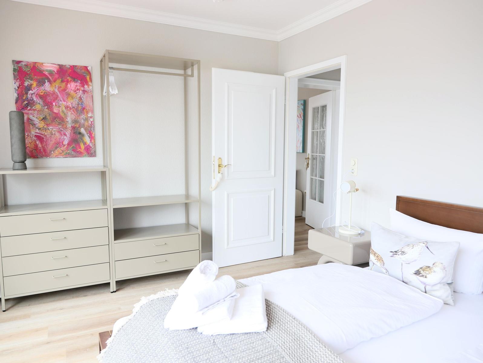 Schlafzimmer mit Bett, Kleiderschrank und Wandbild.