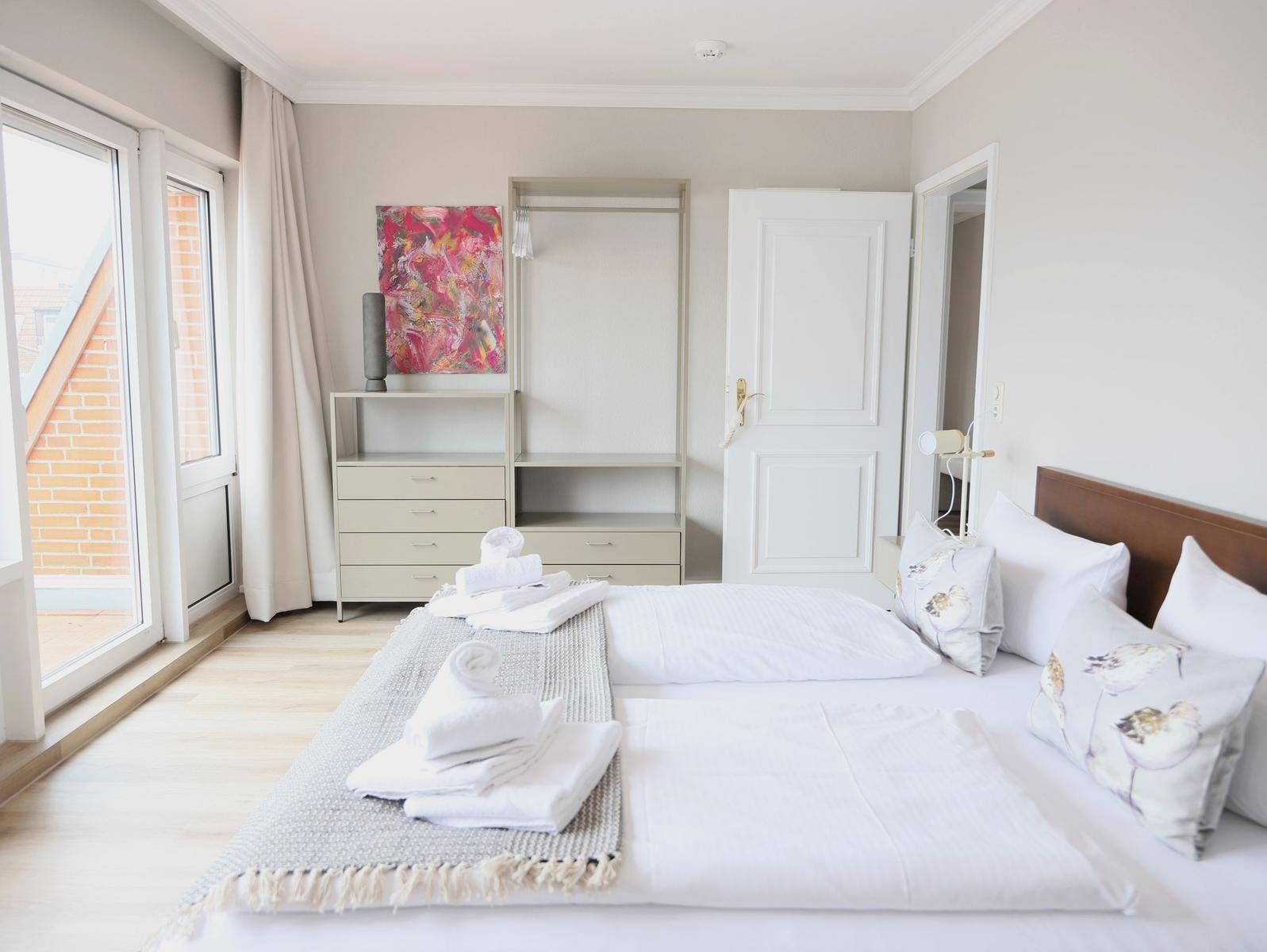 Schlafzimmer mit Bett, Kleiderschrank und Fenster zur Terrasse.