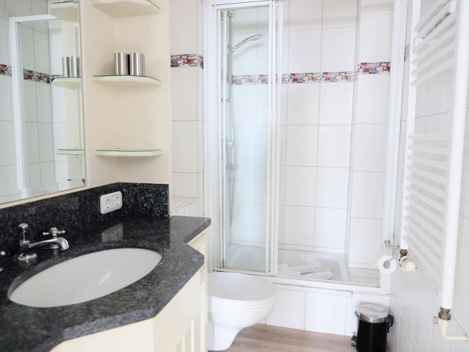 Badezimmer mit Dusche, Waschbecken und Toilette.