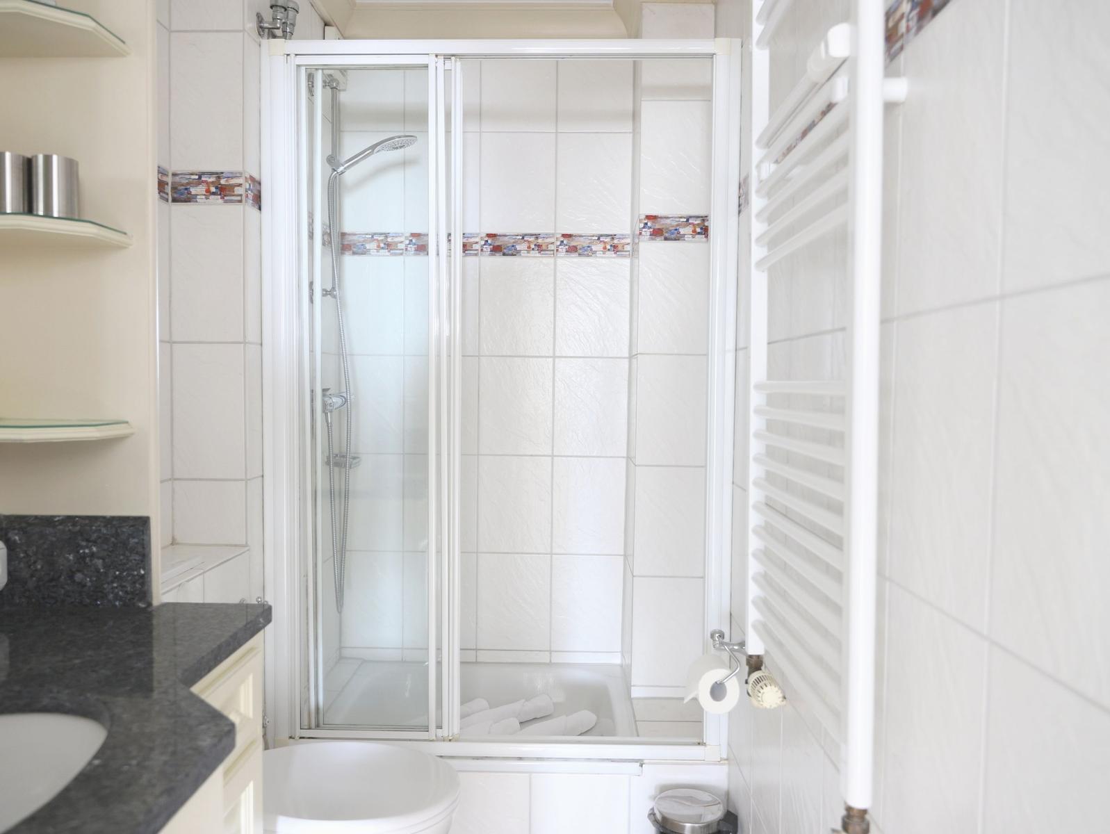 Badezimmer mit Dusche, Waschbecken und Heizung.