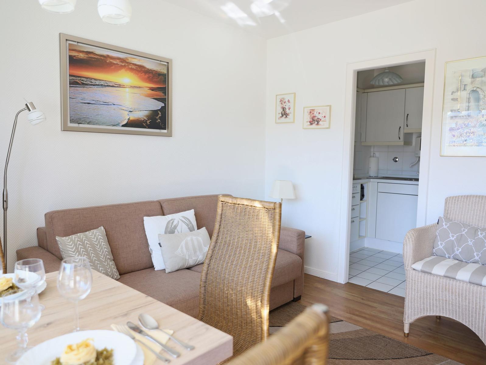 Living and dining area with sofa, chair, and view into the kitchen.