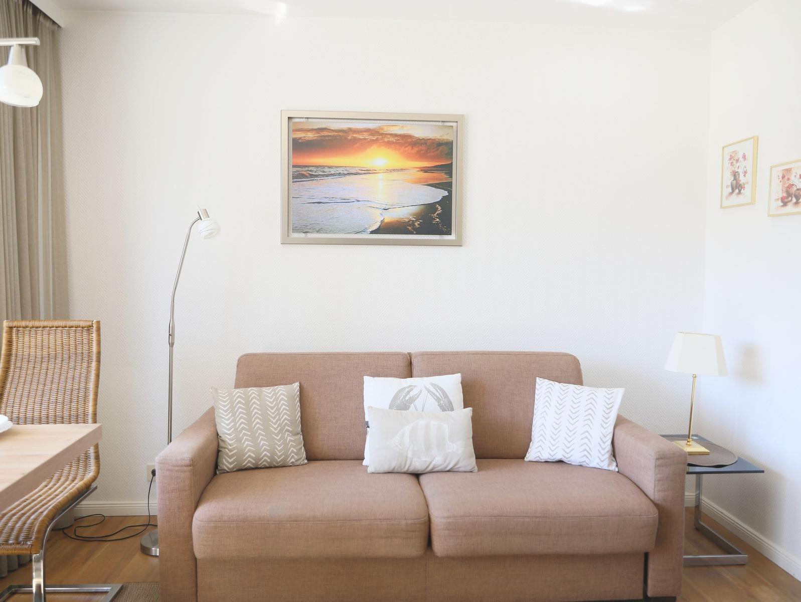A sofa with cushions, wall art, and a floor lamp in the living room.