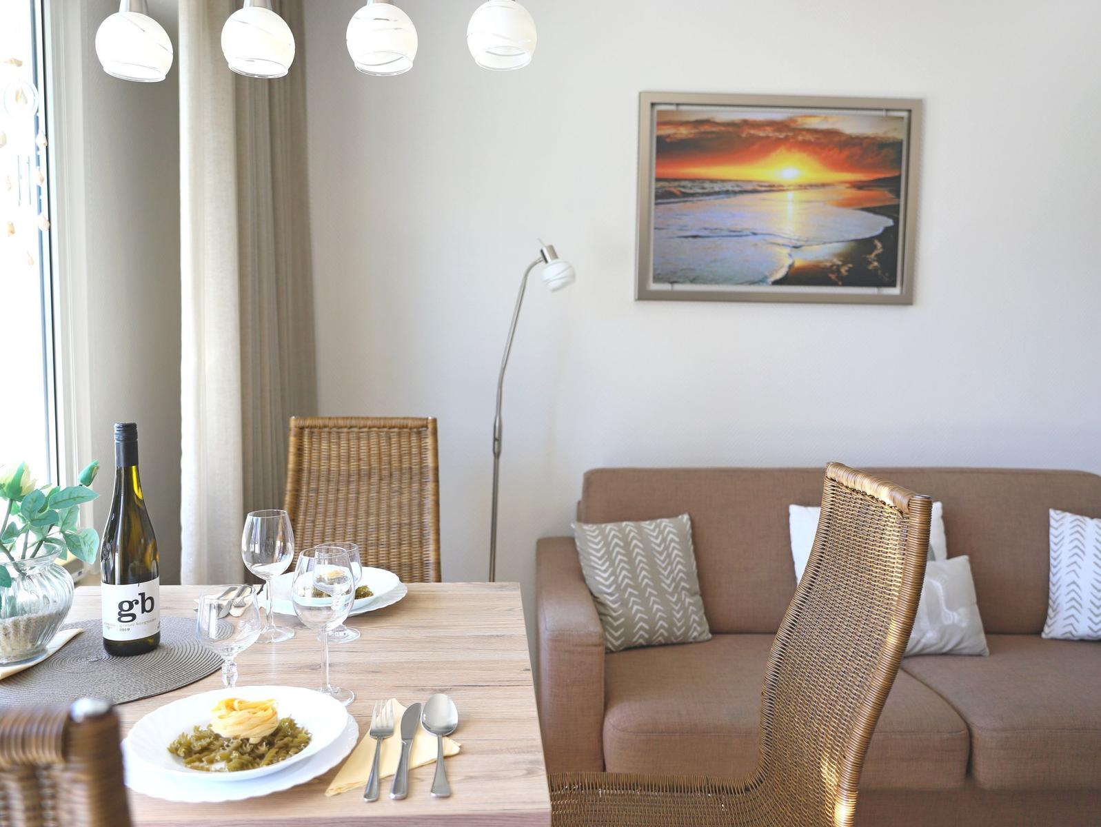 Dining table for two, beside sofa with cushions and wall picture.