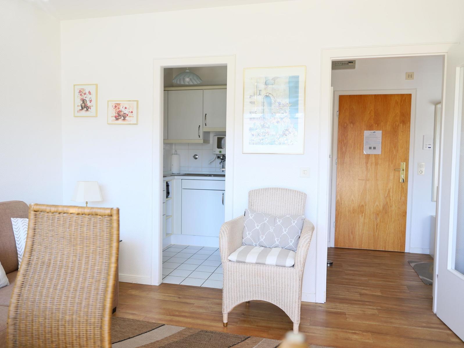 Living area with seating, kitchen area, and entrance door.