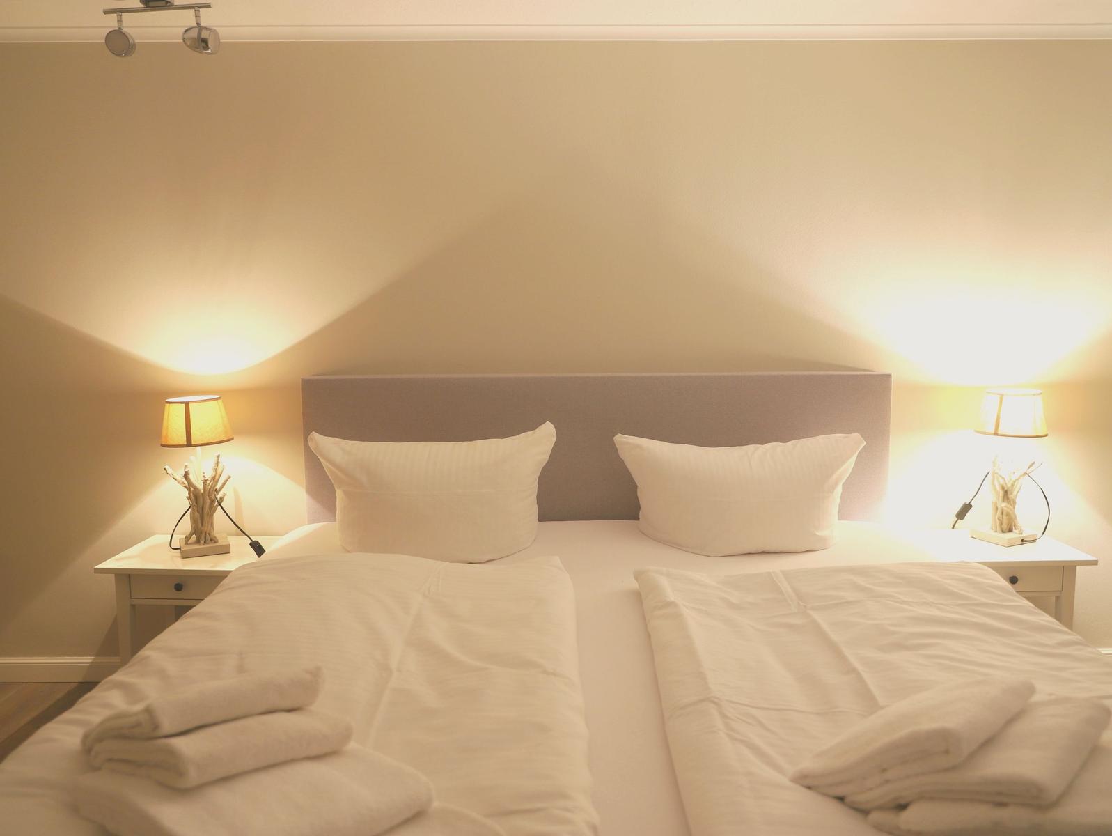 Schlafzimmer mit Doppelbett, zwei Nachttischen und Lampen.