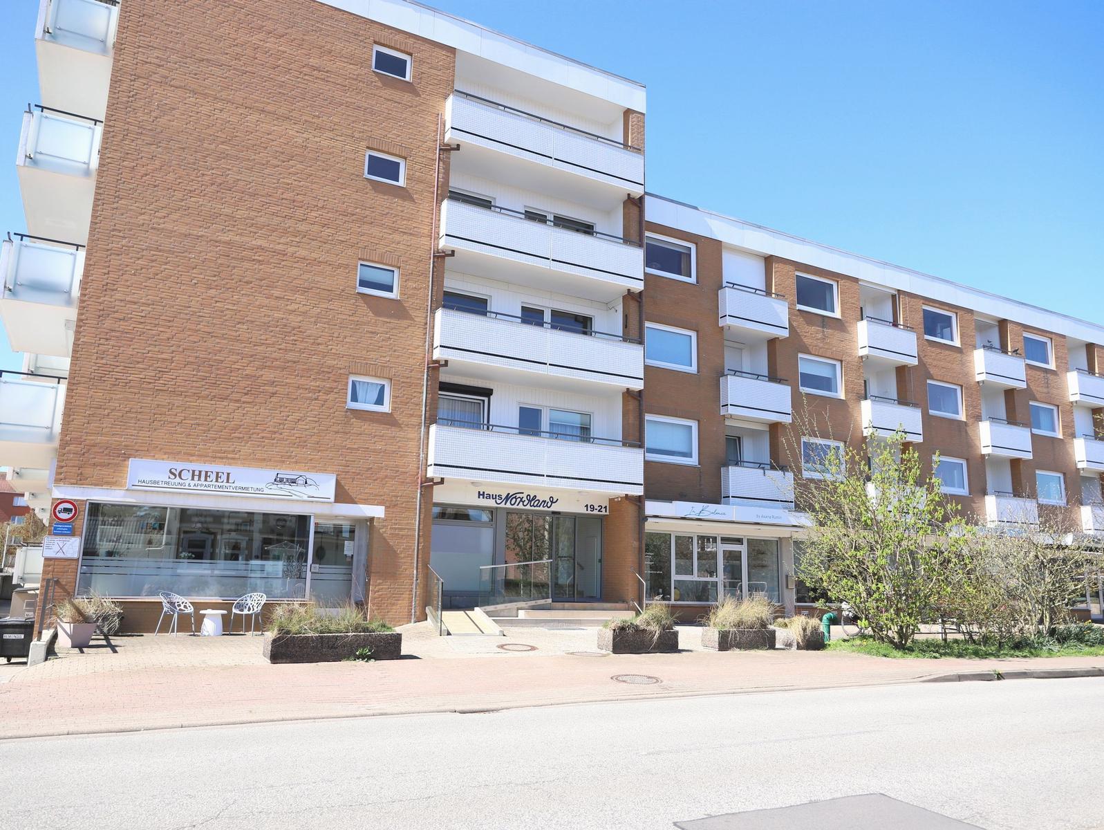 Facade of a multi-story building with balconies and entrance area.
