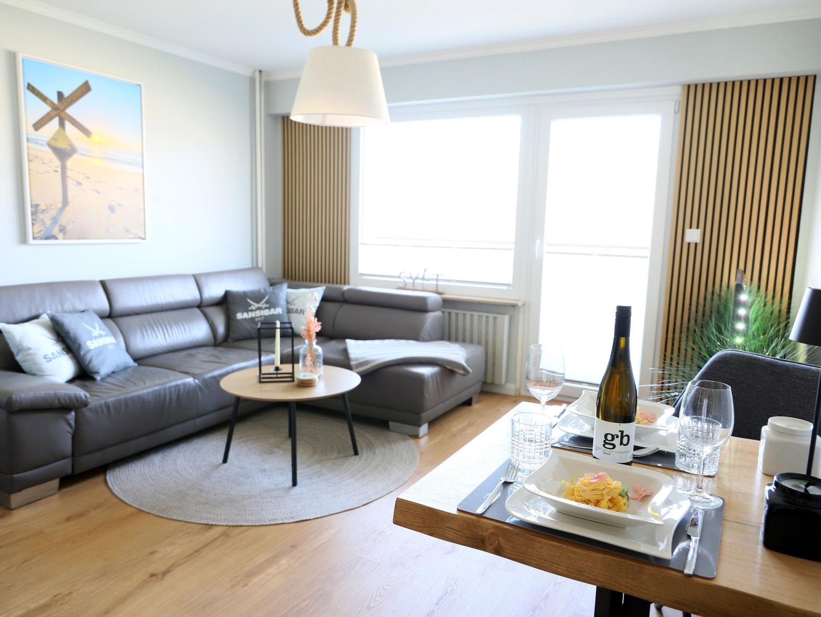 Wohn- und Essbereich mit Sofa, Tisch und Fenster.