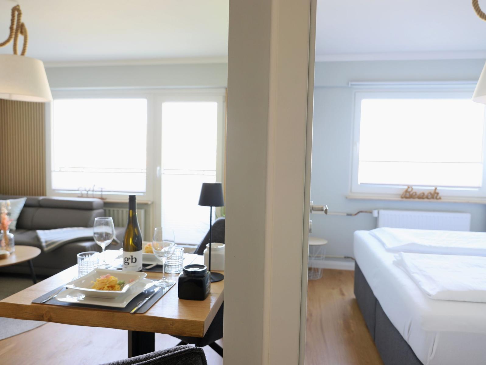 Wohn- und Schlafzimmer mit Tisch, Bett und Fenster. Einrichtung modern und funktional.