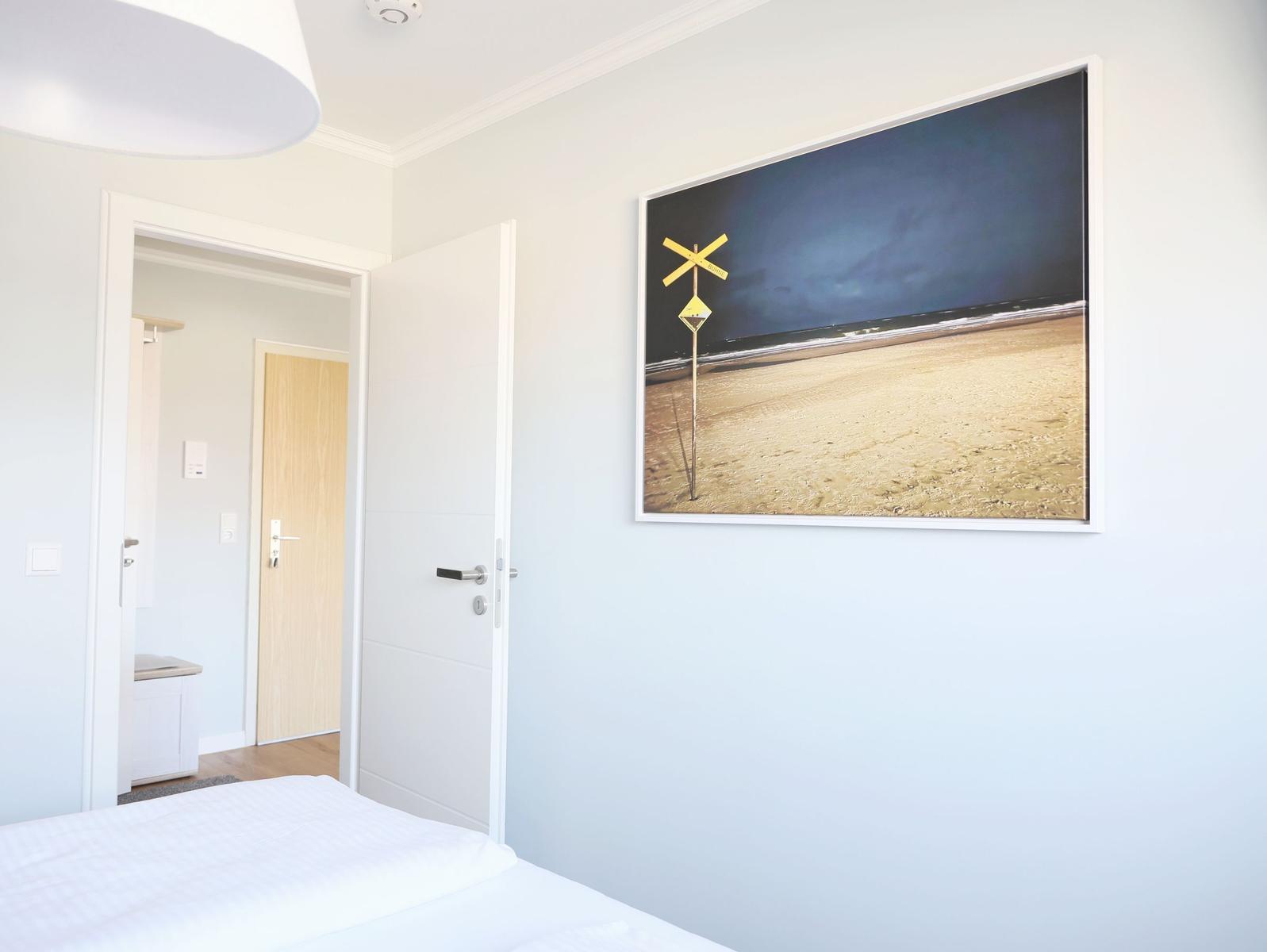 Schlafzimmer mit Bett, Tür und Wandbild mit Bahnübergang.