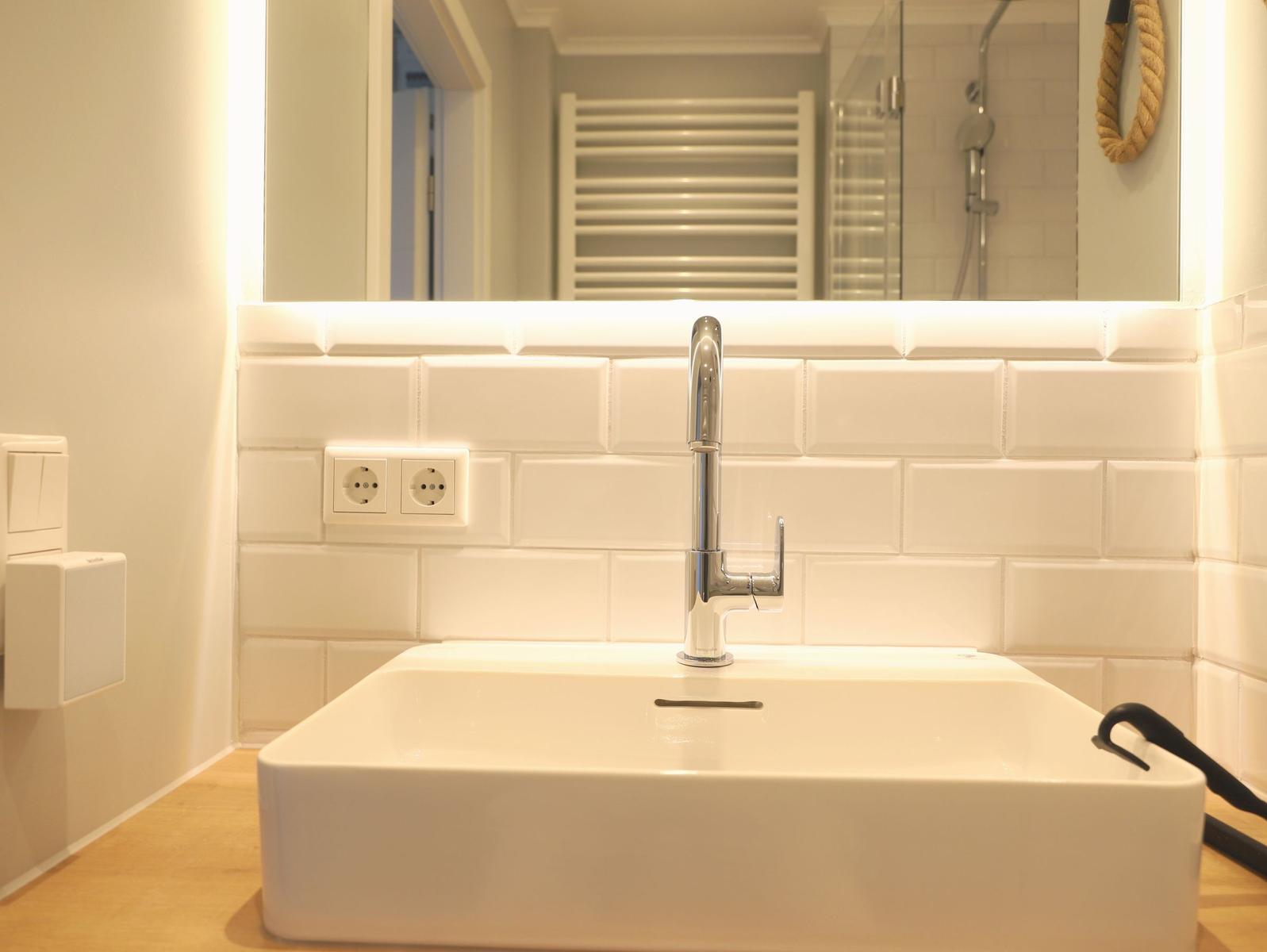 Waschbecken mit Spiegel und modernem Wasserhahn
