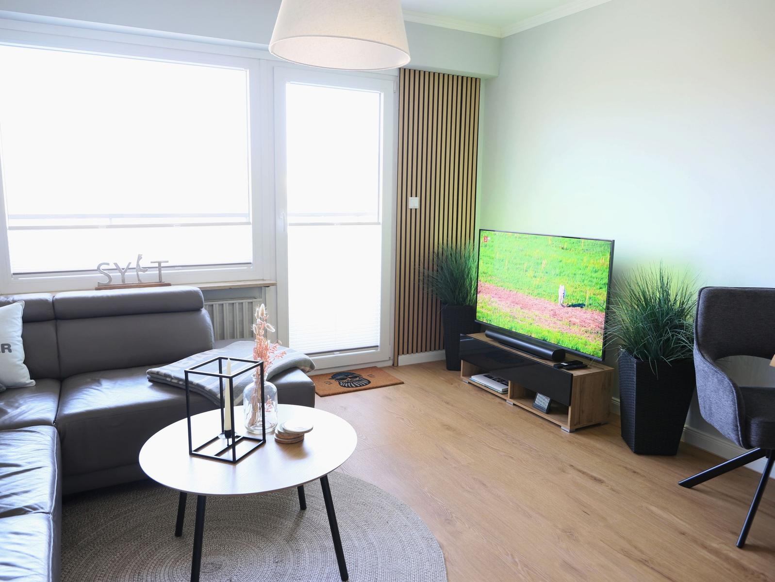 Wohnzimmer mit Sofa, Fernseher und Pflanzen.