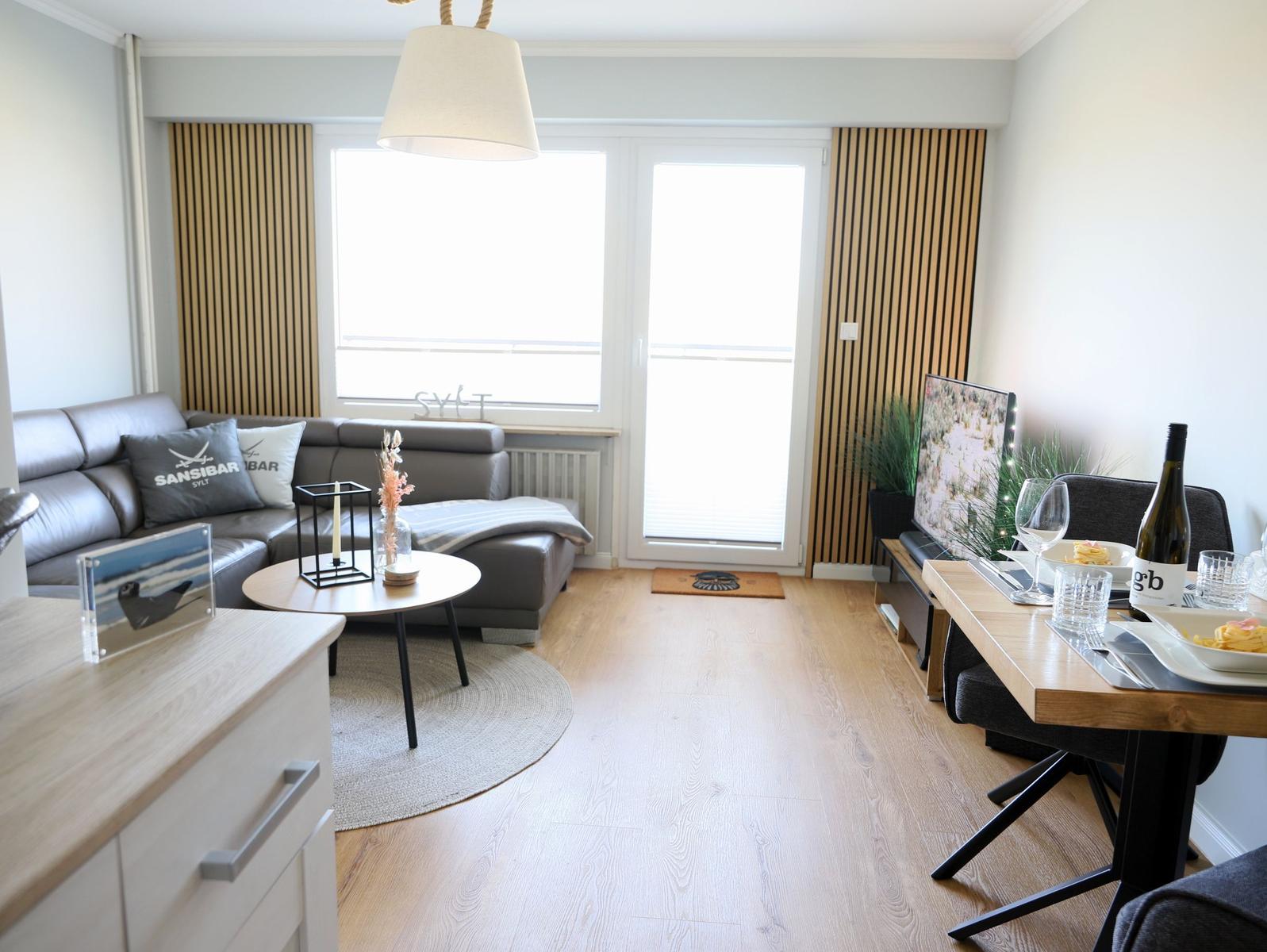 Wohn- und Essbereich mit Sofa, Tisch und Fenster zur Terrasse.