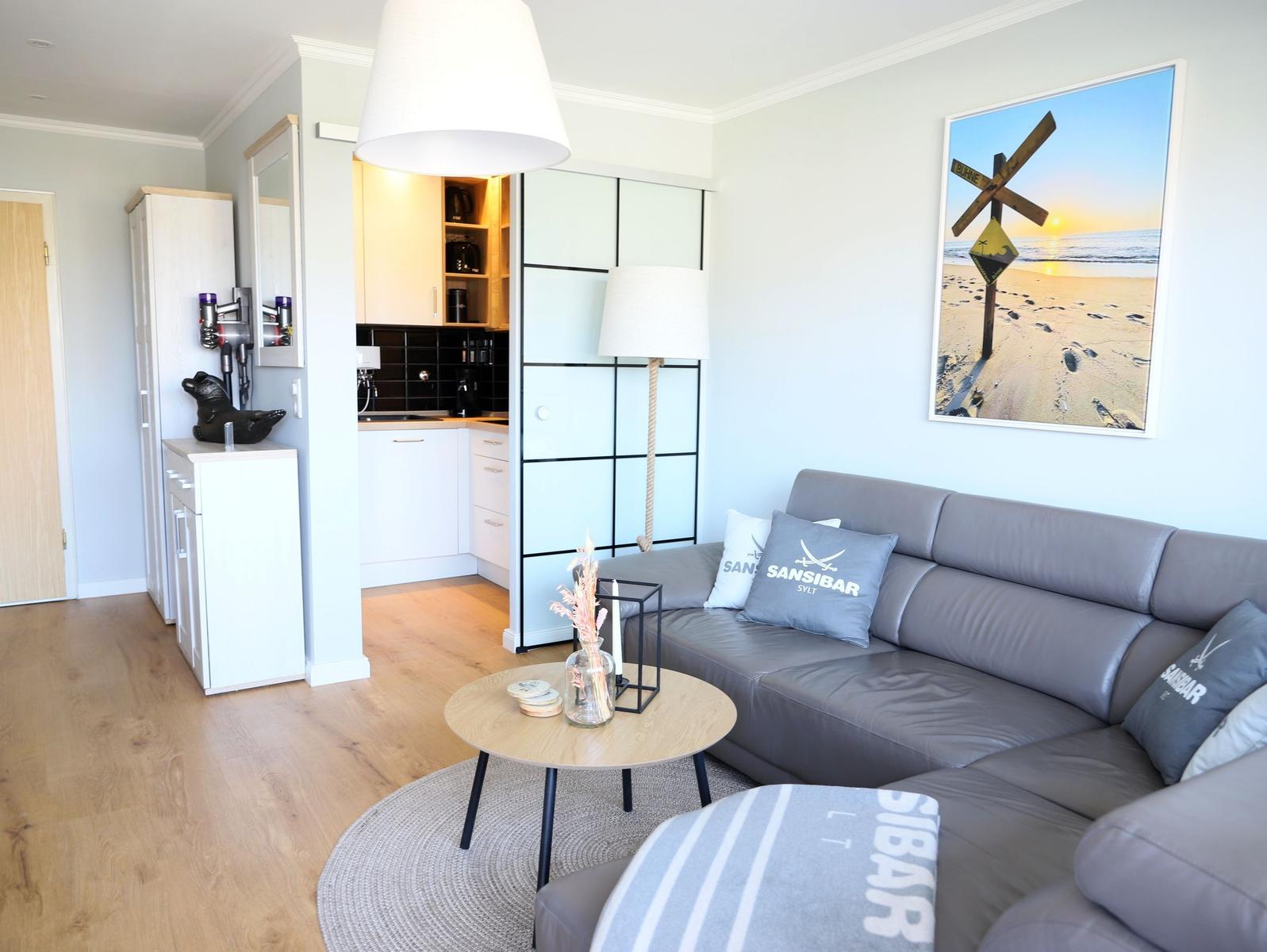 Wohnzimmer mit Sofa, Couchtisch und Küchenbereich im Hintergrund.