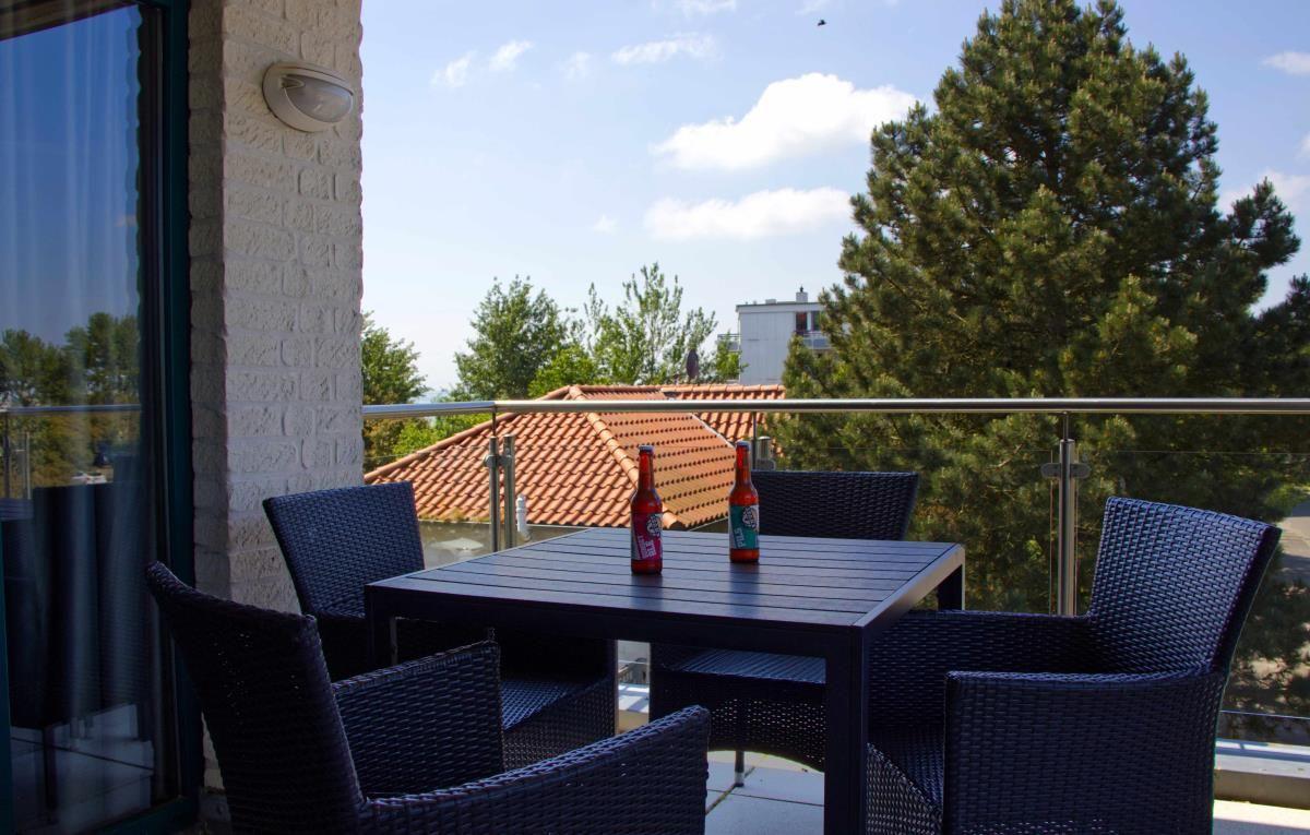 Terrasse mit Tisch und Stühlen, Blick auf Dächer und Bäume.