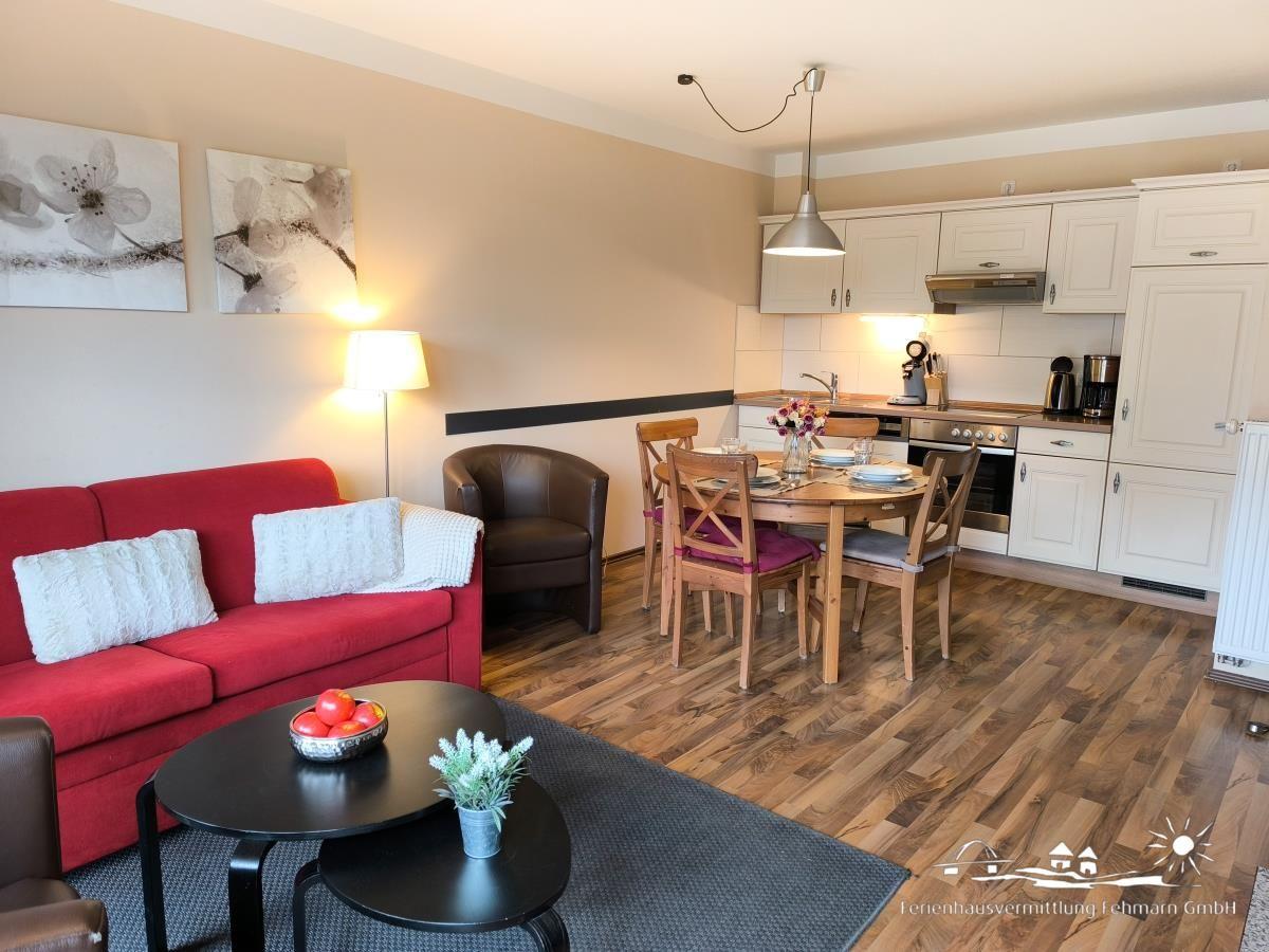 Wohnzimmer mit rotem Sofa, Esstisch und Küche im offenen Raum.