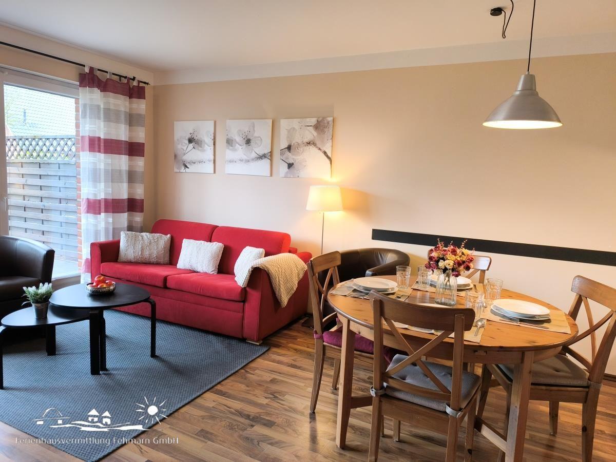 Wohn- und Essbereich mit rotem Sofa, Holztisch und Fensterblick.
