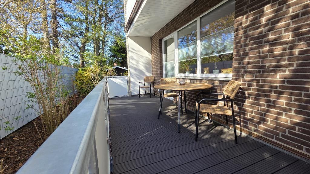 Terrace with table and chairs next to brick wall and windows.