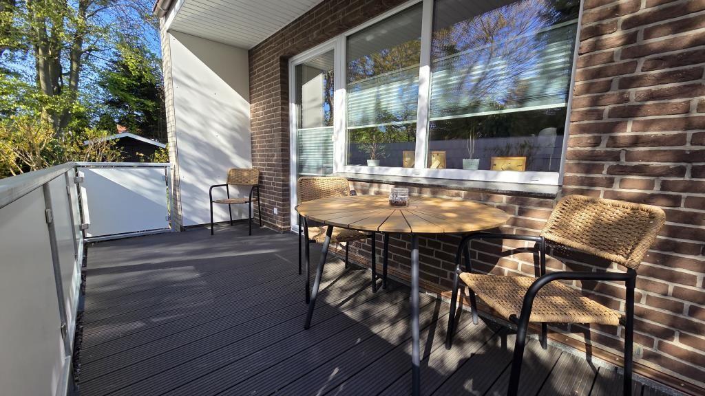 Deck with wooden table and chairs, adjacent to living area with window.