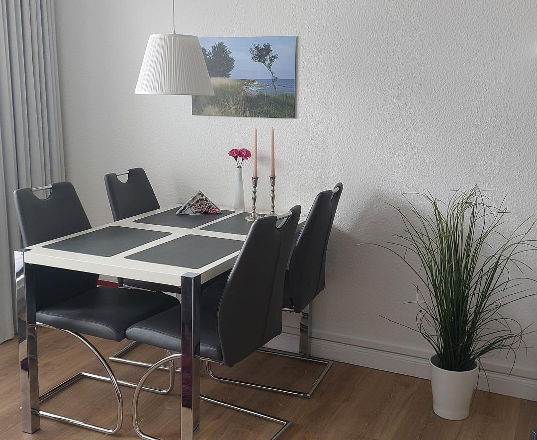 Esstisch mit sechs Stühlen, Wandbild und Pflanze
