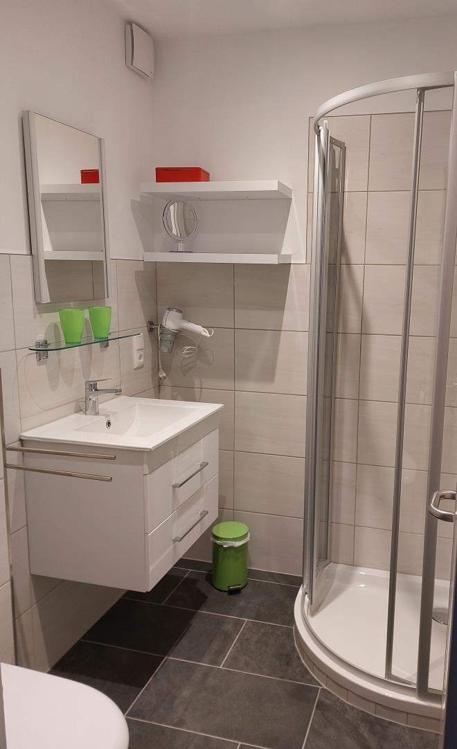 Badezimmer mit Dusche, Waschbecken und Spiegel