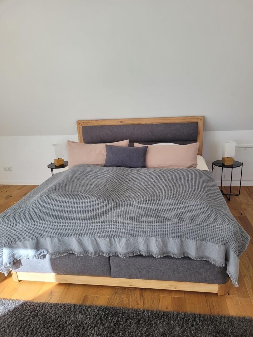 Schlafzimmer mit Bett, Holzboden und zwei Nachttischen mit Lampen.