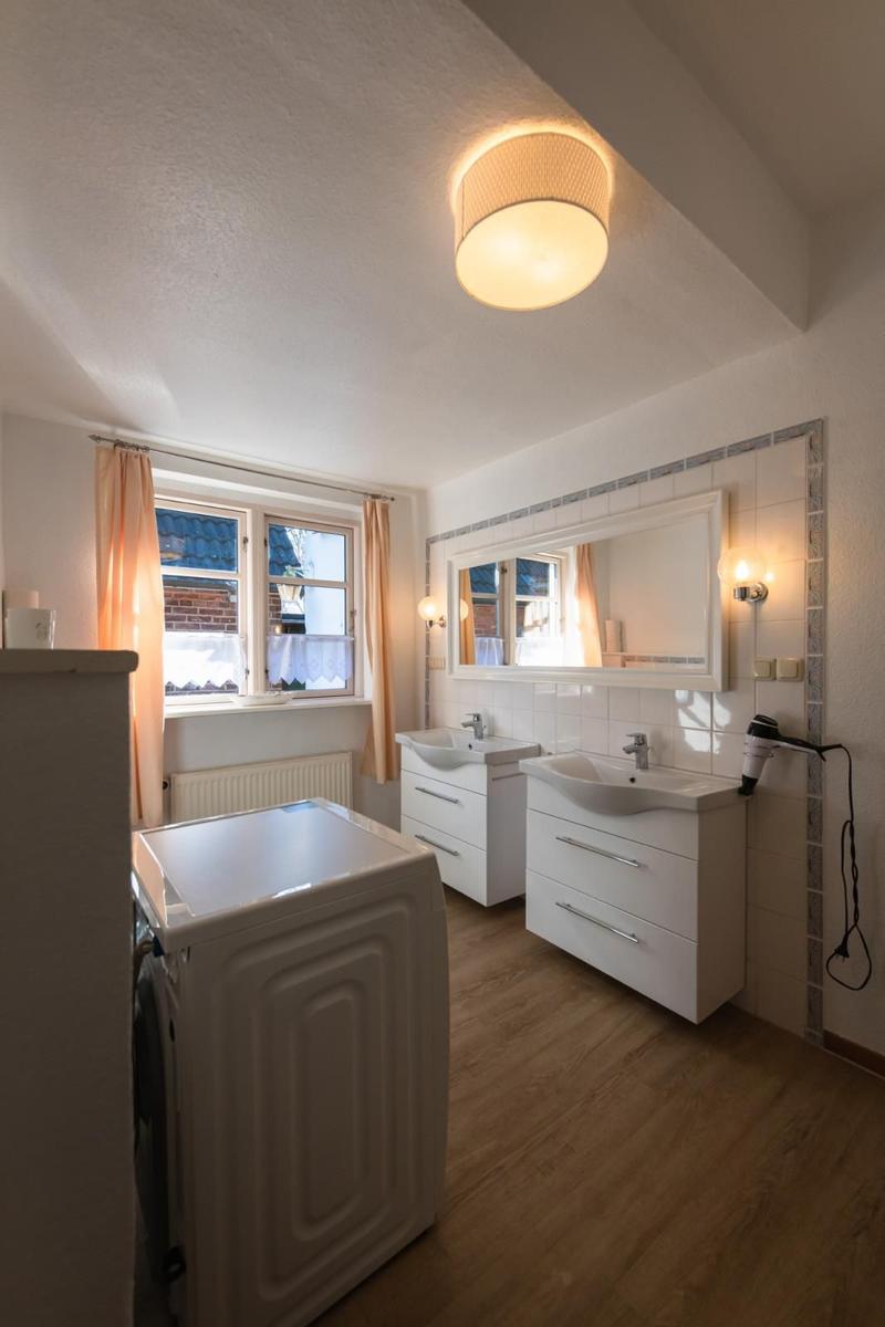 Badezimmer mit zwei Waschbecken, Spiegel, Fenster und Trockner.