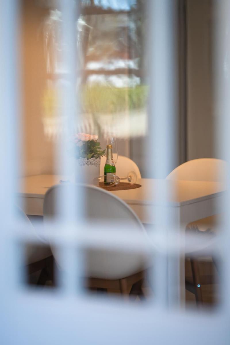 Essbereich mit Tisch, Stühlen und Flasche hinter Fenster