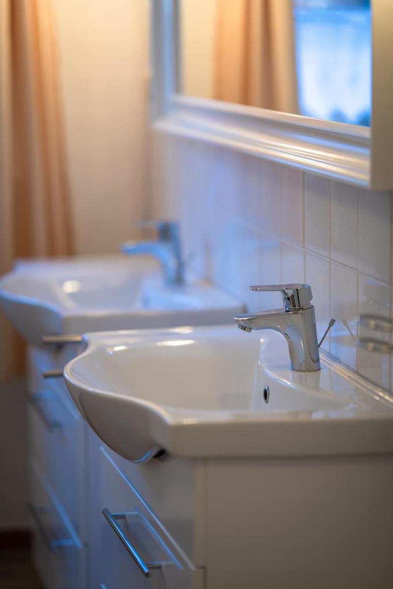 Zwei weiße Waschbecken mit Chromhähnen und Spiegeln an der Wand.