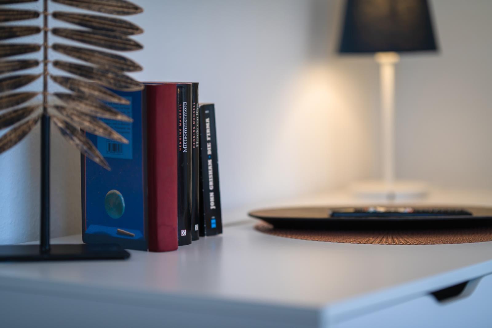 Nachttisch mit Buchregal, Lampe und Fernbedienung.