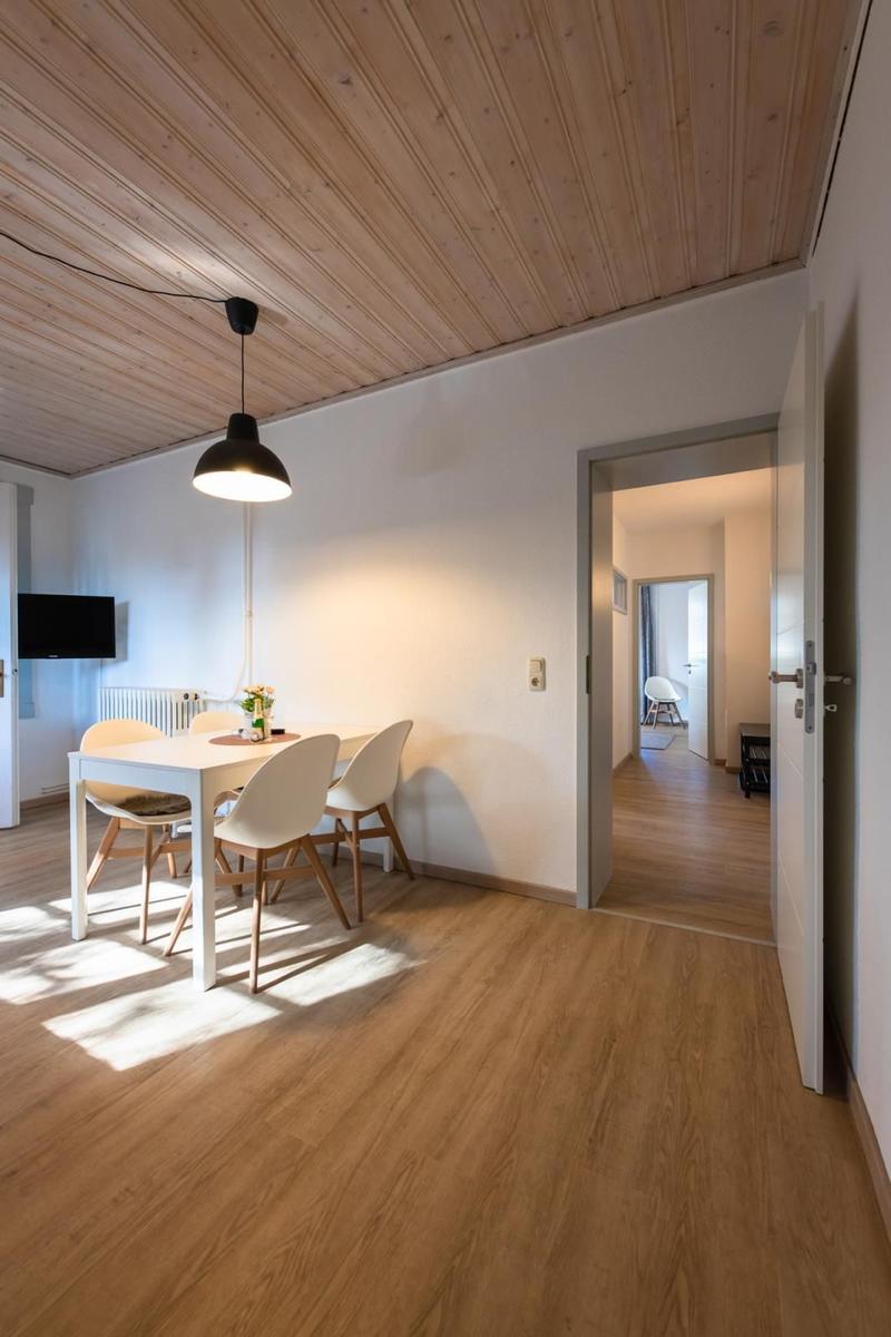 Essbereich mit Tisch, Stühlen und Fernseher unter Holzdecke.
