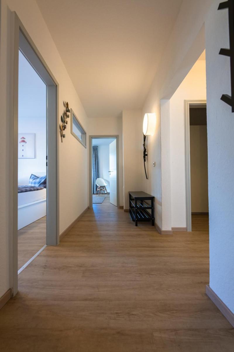 Flur mit Holzboden, Wandbeleuchtung und Sicht in Schlafzimmer und Wohnbereich.