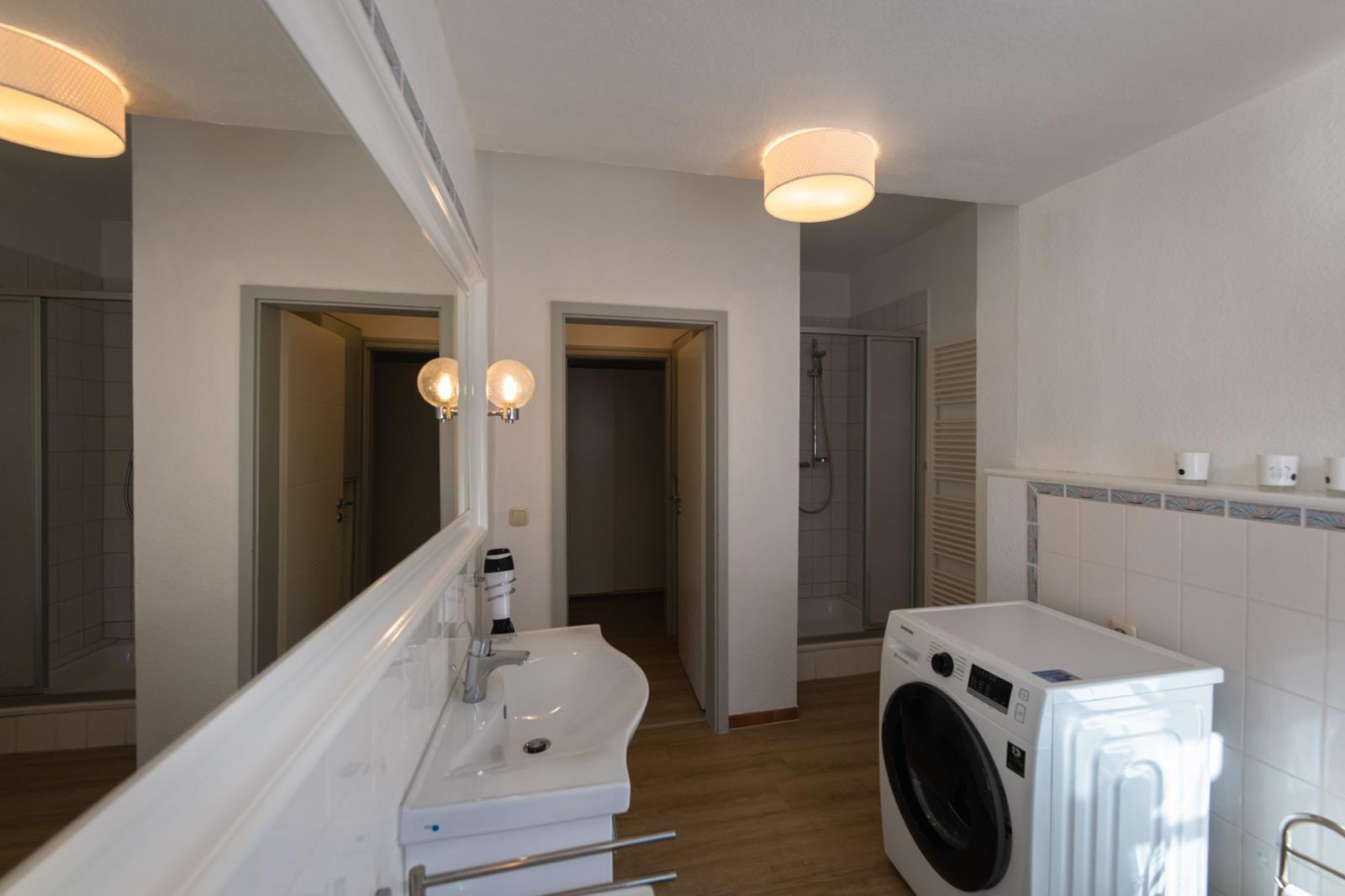 Badezimmer mit Waschmaschine, Spiegel und Dusche
