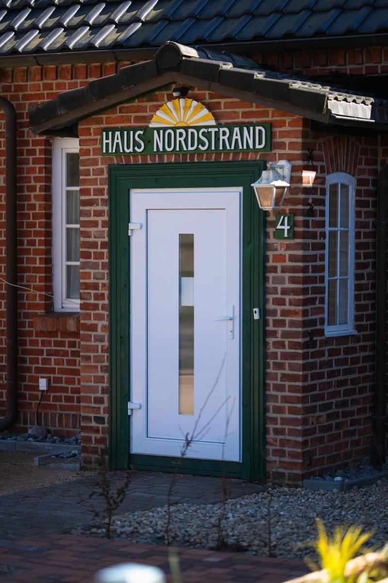 Entrance door with sign Haus Nordstrand on a red brick house.