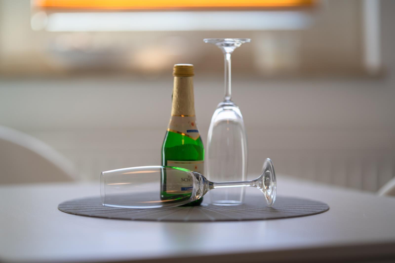 On the table is a green bottle and two champagne glasses.