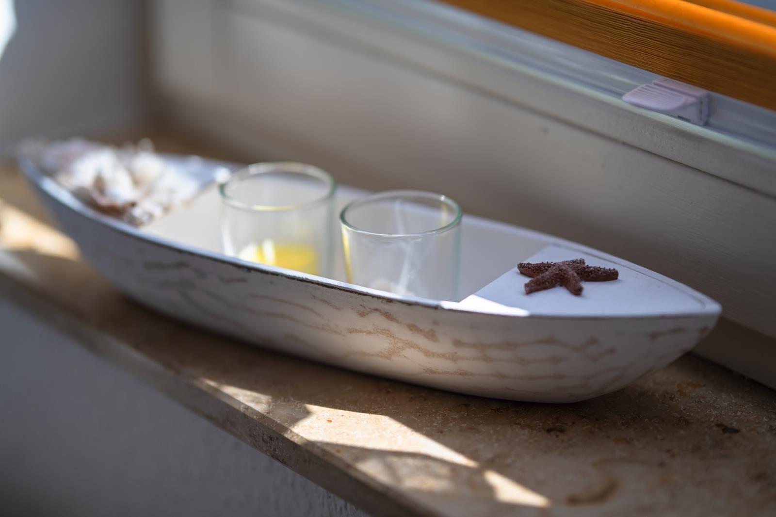 A white boat with two glasses and a starfish on a windowsill.
