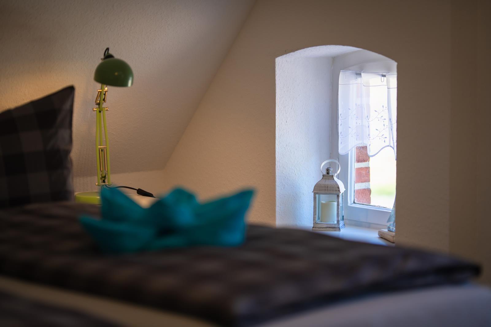 Bedroom with bed, green lamp, and window with lantern.