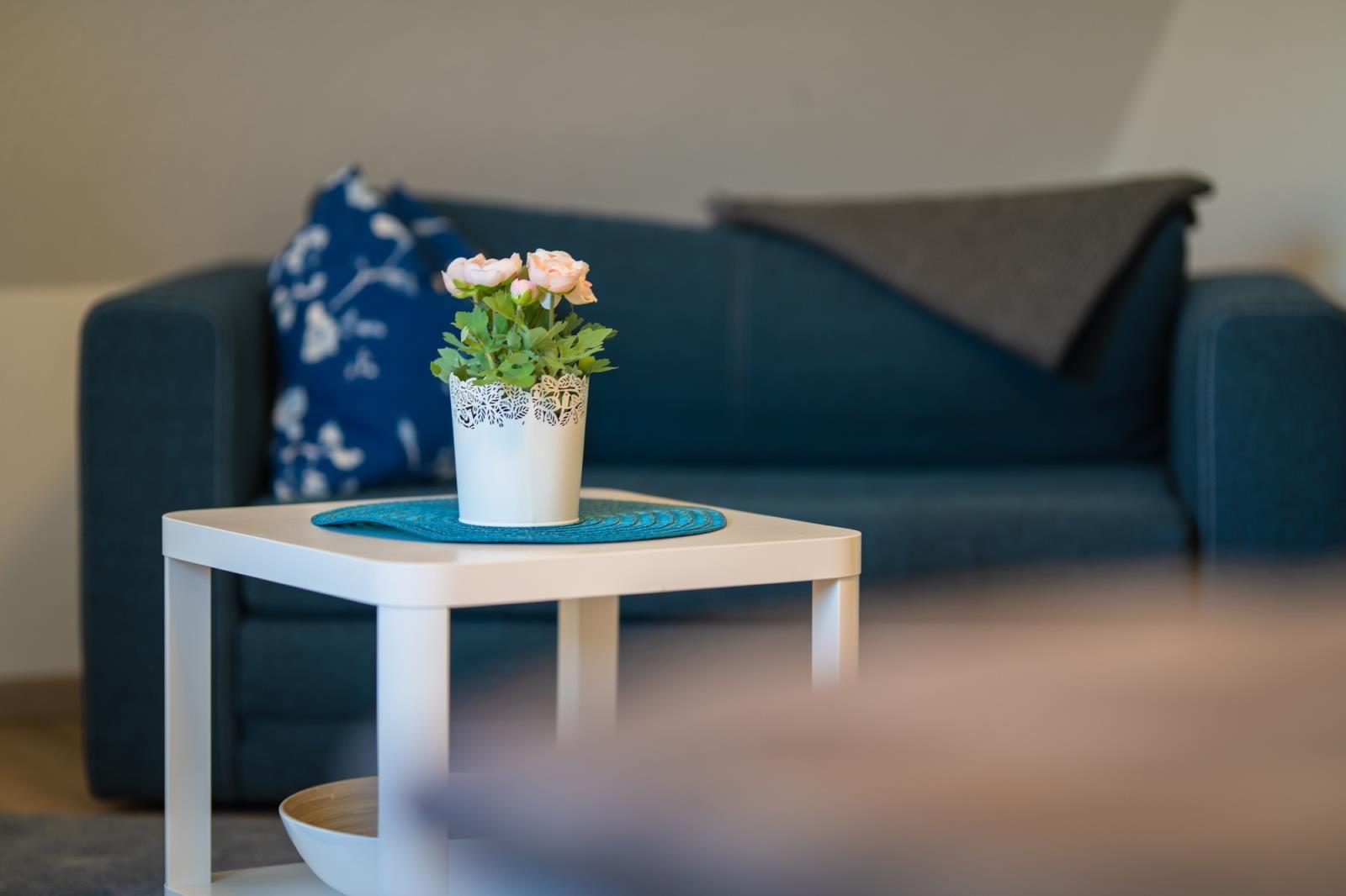 A white table with flowers in front of a blue sofa