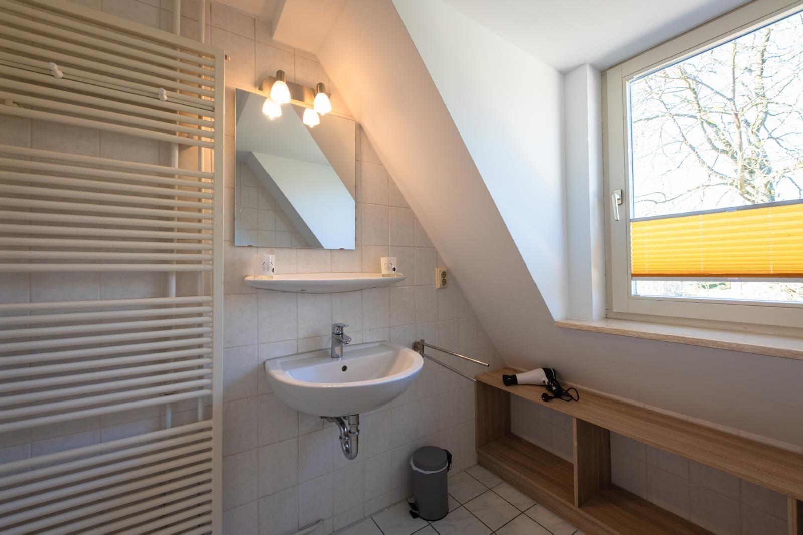 Bathroom with sink, mirror, heater, and window with blind.