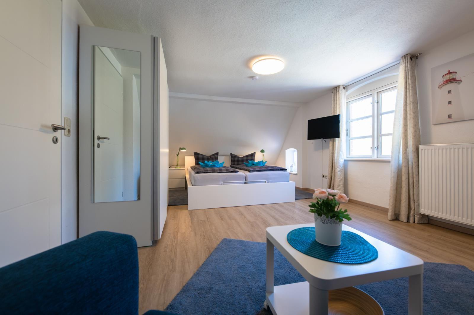 Bedroom with double bed, TV, and window with curtains.