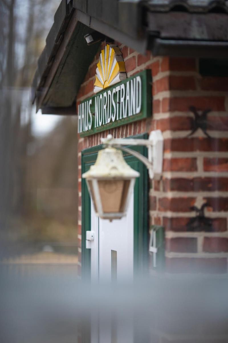 Haus Nordstrand with brick facade, green door, and lantern.