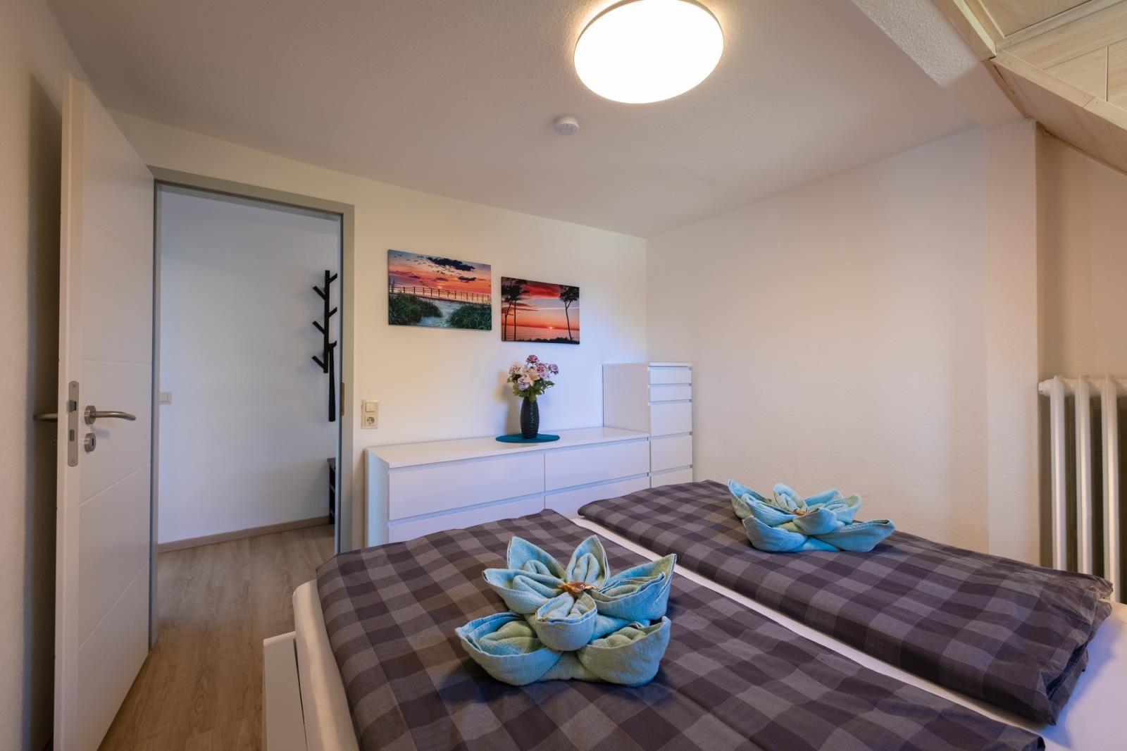 Schlafzimmer mit Doppelbett, weißen Schränken und Wandbildern.
